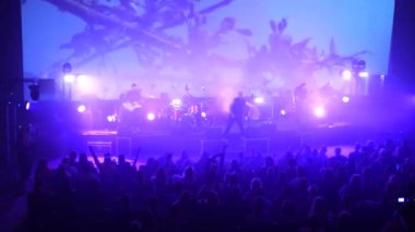 Canlı performans enerjisiyle dolu canlı bir konser salonu. Canlı bir ışık ve ses gösterisi, kalabalığı büyülüyor. Sahnede bir rock grubu çalıyor. Bando sahneyi ateşlerken elektrik enerjisi mekanı dolduruyor..