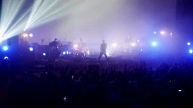 Canlı performans enerjisiyle dolu canlı bir konser salonu. Canlı bir ışık ve ses gösterisi, kalabalığı büyülüyor. Sahnede bir rock grubu çalıyor. Bando sahneyi ateşlerken elektrik enerjisi mekanı dolduruyor..