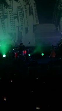 Dikey, canlı performans enerjisiyle canlı bir konser salonu. Canlı bir ışık ve ses gösterisi, kalabalığı büyülüyor. Sahnede bir rock grubu çalıyor. Elektrik enerjisi mekanı dolduruyor