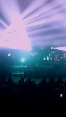 Dikey, canlı performans enerjisiyle canlı bir konser salonu. Canlı bir ışık ve ses gösterisi, kalabalığı büyülüyor. Sahnede bir rock grubu çalıyor. Elektrik enerjisi mekanı dolduruyor
