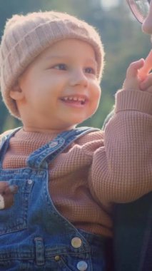 Bir baba bebeğini kucağına alır, sonbaharın altın ışığında yıkanır. Parkta sıcacık bir kucaklaşma, sonbahar renkleri etraflarında yavaşça bulanıklaşıyor. O ve oğlu, doğanın kucakladığı bir anı paylaşıyorlar. Nazik eller.,