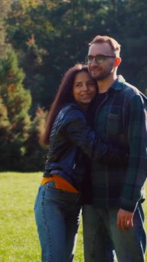 Dikey. Güneşten sırılsıklam olmuş bir parkta bir erkekle bir kadının yakın kucaklaşması. Mutlu sevgili çift, sonbahar yaprakları arasında hassas bir anı paylaşıyor. Yüzler birbirine yakın, parkın kollarında bir bağ hissedildi..