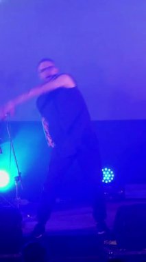 Dikey olarak, bir rock grubu sahnede çalıyor. Dinleyiciler ellerini kaldırdı ve bir müzik grubunun rock konserine atladı. Grubun solisti, vokalisti izleyicilerle birlikte şarkı söylüyor. Davulcu, gitarist., 