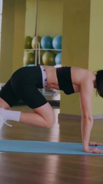 Dikey. Dinamik egzersiz pozu veren bir kadın. Stüdyo çalışması, hareket halindeki bir kadın vücudu. Fitness rutini. Zorlu bir egzersizde bir kadın vücudu. Bir kadın fiziksel egzersiz yapıyor. esneme, spor modeli