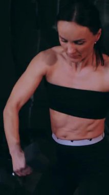 Dikey. Sporcu spor salonunda egzersizler yapar. Bir kadın kaslarını ve vücudunu eğitir. Seksi genç kadın spor salonunda simülatörlerle meşgul. Güzel spor vücudu..