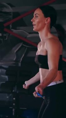 Dikey. Sporcu spor salonunda egzersizler yapar. Bir kadın kaslarını ve vücudunu eğitir. Seksi genç kadın spor salonunda simülatörlerle meşgul. Güzel spor vücudu..