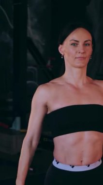 Dikey. Sporcu spor salonunda egzersizler yapar. Bir kadın kaslarını ve vücudunu eğitir. Seksi genç kadın spor salonunda simülatörlerle meşgul. Güzel spor vücudu..
