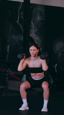Dikey. Sporcu spor salonunda egzersizler yapar. Bir kadın kaslarını ve vücudunu eğitir. Seksi genç kadın spor salonunda simülatörlerle meşgul. Güzel spor vücudu..