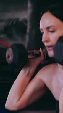 Dikey. Sporcu spor salonunda egzersizler yapar. Bir kadın kaslarını ve vücudunu eğitir. Seksi genç kadın spor salonunda simülatörlerle meşgul. Güzel spor vücudu..