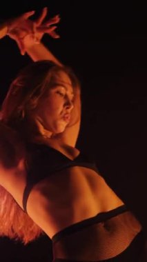 Dikey, baştan çıkarıcı dans eden seksi kadın. Büyük kalçalı, tangalı bir dansçı kız karanlık bir salonda erotik bir şekilde dans ediyor. Twerk, yüksek topuklu, striptiz