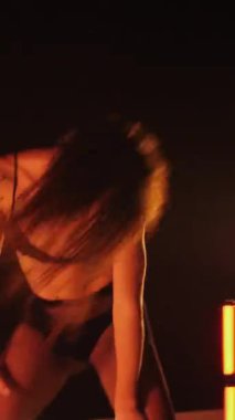 Dikey, baştan çıkarıcı dans eden seksi kadın. Büyük kalçalı, tangalı bir dansçı kız karanlık bir salonda erotik bir şekilde dans ediyor. Twerk, yüksek topuklu, striptiz
