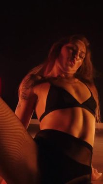 Dikey, baştan çıkarıcı dans eden seksi kadın. Büyük kalçalı, tangalı bir dansçı kız karanlık bir salonda erotik bir şekilde dans ediyor. Twerk, yüksek topuklu, striptiz