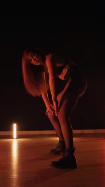 Dikey, baştan çıkarıcı dans eden seksi kadın. Büyük kalçalı, tangalı bir dansçı kız karanlık bir salonda erotik bir şekilde dans ediyor. Twerk, yüksek topuklu, striptiz