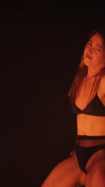 Dikey, baştan çıkarıcı dans eden seksi kadın. Büyük kalçalı, tangalı bir dansçı kız karanlık bir salonda erotik bir şekilde dans ediyor. Twerk, yüksek topuklu, striptiz