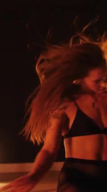 Dikey, baştan çıkarıcı dans eden seksi kadın. Büyük kalçalı, tangalı bir dansçı kız karanlık bir salonda erotik bir şekilde dans ediyor. Twerk, yüksek topuklu, striptiz