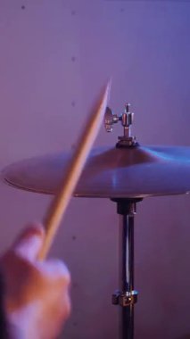 Dikey. Stüdyoda bir adam davul çalıyor. Sürücü müzisyen davulcu soğukkanlılıkla davulda rock çalar. Stüdyo, renk arkaplanı.