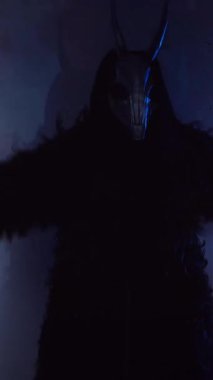 Dikey olarak şeytan elinde RGB çubuklarıyla dans ediyor. Karanlık bir stüdyoda maskeli gizemli bir adam. Adam siyah bir ceket ve boynuzlu bir maske giymiş. Uzaylı uzaylı. Korkunç.,