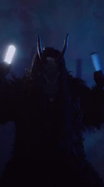 Dikey olarak şeytan elinde RGB çubuklarıyla dans ediyor. Karanlık bir stüdyoda maskeli gizemli bir adam. Adam siyah bir ceket ve boynuzlu bir maske giymiş. Uzaylı uzaylı. Korkunç.,