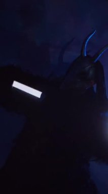 Dikey olarak şeytan elinde RGB çubuklarıyla dans ediyor. Karanlık bir stüdyoda maskeli gizemli bir adam. Adam siyah bir ceket ve boynuzlu bir maske giymiş. Uzaylı uzaylı. Korkunç.,
