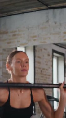 Dikey. Spor salonunda halterle çömelmiş bir kadın. Spor meraklısı ağırlıklarla çömelme hareketi yapıyor. Güçlü kadın antrenmanda halter kaldırıyor. Spor salonunda halterle egzersiz yapan bir kadın. Kadın spor salonunda vücut egzersizi yapıyor.