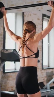 Dikey. Spor salonunda halterle çömelmiş bir kadın. Spor meraklısı ağırlıklarla çömelme hareketi yapıyor. Güçlü kadın antrenmanda halter kaldırıyor. Spor salonunda halterle egzersiz yapan bir kadın. Kadın spor salonunda vücut egzersizi yapıyor.