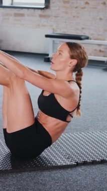 Dikey. Fitness meraklısı spor salonunda vücut egzersizi yapıyor. Kadın spor salonunda çekirdek egzersizi yapıyor. Spor salonunda spor yapan spor meraklısı. Egzersiz yapan bir kadın. Jimnastik. Antrenmandaki kuvvet