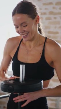Dikey. Spor kıyafetli bir kadın egzersiz minderinde mekik çekiyor. Koltuk değnekli karın kasları üzerinde çalışan bir bayan sporcu. Fitness meraklısı spor salonunda vücut egzersizi yapıyor. mekik çekerken karın kaslarına odaklanan kadın..