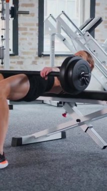 Dikey. Spor kıyafetli bir kadın egzersiz minderinde mekik çekiyor. Koltuk değnekli karın kasları üzerinde çalışan bir bayan sporcu. Fitness meraklısı spor salonunda vücut egzersizi yapıyor. mekik çekerken karın kaslarına odaklanan kadın..