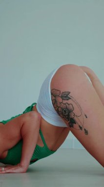 Dikey. Yeşil bluzlu, beyaz şortlu güzel bir kadın poz veriyor ve vücudunu esnetiyor. Koca kalçalı bir dansçı kız baştan çıkarıcı bir dans yapar. Yüksek topuklar