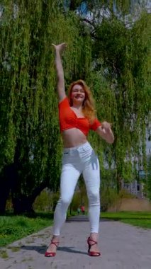 Dikey. Güzel enerjik kadın dışarıda salsa yapıyor. Bachata yapan genç bir kadın, açık gökyüzünün altında parkta kizomba yapıyor. Şehrin kaldırımında ateşli bir kadının baştan çıkarıcı dansı..