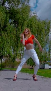 Dikey. Güzel enerjik kadın dışarıda salsa yapıyor. Bachata yapan genç bir kadın, açık gökyüzünün altında parkta kizomba yapıyor. Şehrin kaldırımında ateşli bir kadının baştan çıkarıcı dansı..
