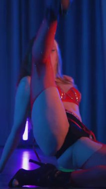 Dikey. Kırmızı iç çamaşırlı, erotik dans eden, yüksek topuklu genç bir kadın. Siyah şortlu yarı traşlı kız karanlık uzayda zarafetle hareket ediyor. Sahnedeki disko kulübünde striptiz..