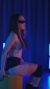 Anime tarzında siyah gözlüklü genç bir kadın erotik bir şekilde dans ediyor. Siyah şortlu yarı traşlı kız karanlık uzayda zarafetle hareket ediyor. Sahnedeki disko kulübünde striptiz..