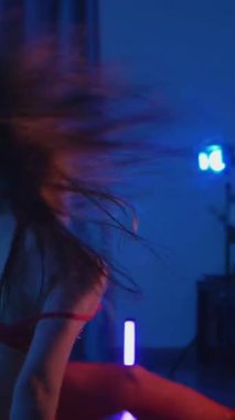 Dikey. Kırmızı iç çamaşırlı, erotik dans eden, yüksek topuklu genç bir kadın. Siyah şortlu yarı traşlı kız karanlık uzayda zarafetle hareket ediyor. Sahnedeki disko kulübünde striptiz..