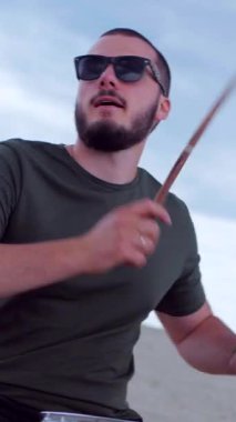 Dikey. Çölde bir müzik grubu çalıyor. Seksi kız bir grupta serin şarkı söyler. Basçı, gitarist, davulcu, profesyonel, konser. Elektro gitar, bas gitar, davul, şarkıcı
