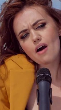Dikey. Seksi kız bir grupta serin şarkı söyler. Müzik grubu stadyumun arka planında çaldı. Şehir merkezinde güzel bir bayan şarkıcı şarkı söyler. Sütyenli bir model bir grupta şarkı söyler..