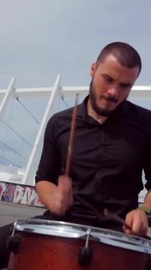 Dikey. Adam soğukkanlılıkla davul çalıyor. Bir müzik grubu stadyumun arka planına karşı meydanda çalar. Profesyonel müzisyen. Meydanda şehir merkezinde bir müzik grubu çalıyor. Profesyonel müzisyen..