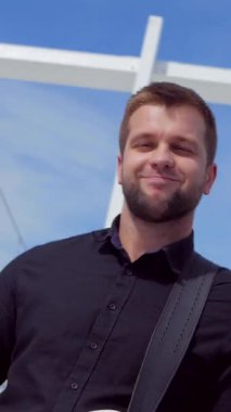Dikey. Adam havalı bas gitar çalıyor. Stadyumun arka planında müzik grubu çalıyor. Profesyonel müzisyen. Meydanda şehir merkezinde bir müzik grubu çalıyor. Profesyonel müzisyen..