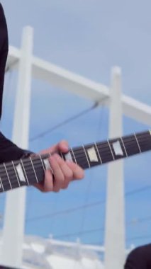 Dikey. Adam havalı bir şekilde stadyumun arka planında elektro gitar çalıyor. Meydanda şehir merkezinde bir müzik grubu çalıyor. Profesyonel müzisyen..