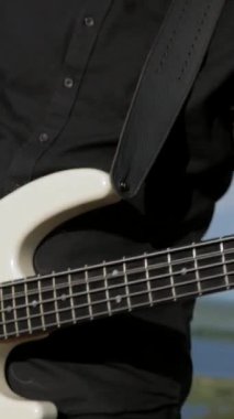 Dikey. Güneşli bir günde bir grup dışarıda canlı çalar. Kadın bir grupta güzel şarkı söylüyor. Grup doğada çalıyor. Basçı, gitarist, davulcu, profesyonel, konser. Güzel manzara.