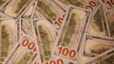 Bir dizi kağıt para dönüyor. Taze basılmış banknotlar. Bir Amerikan doları koleksiyonu, zenginliğin ve fırsatların sembolü. Dolar, Amerikan para biriminde birbirine karışmış. Çeşitli mezheplerin yakın plan görüntüsü