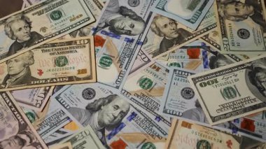 Bir dizi kağıt para dönüyor. Taze basılmış banknotlar. Bir Amerikan doları koleksiyonu, zenginliğin ve fırsatların sembolü. Dolar, Amerikan para biriminde birbirine karışmış. Çeşitli mezheplerin yakın plan görüntüsü