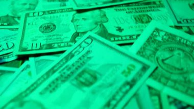 Bir dizi kağıt para dönüyor. Taze basılmış banknotlar. Bir Amerikan doları koleksiyonu, zenginliğin ve fırsatların sembolü. Dolar, Amerikan para biriminde birbirine karışmış. Çeşitli mezheplerin yakın plan görüntüsü