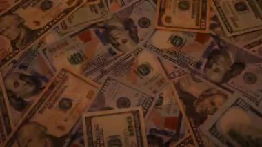 Canlı bir Amerikan para akışı var. Çok renkli ışıkta yıkanmış bir Amerikan doları yağmuru. ABD banknotlarının yakın plan görüntüsü. Detayları renkli bir renge bürünmüş. kağıt para döner.