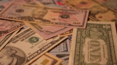 Canlı bir Amerikan para akışı var. Çok renkli ışıkta yıkanmış bir Amerikan doları yağmuru. ABD banknotlarının yakın plan görüntüsü. Detayları renkli bir renge bürünmüş. kağıt para döner.
