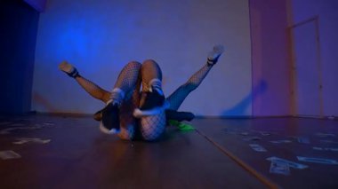 Seksi kızlar erotik dans eder. Kadınlar twerk dansı yapar. Dansçı stüdyoda cinsel olarak hareket eder. Maskeli dansçılar, dengeli ve dinamik, loş sahneyi yönetiyorlar. Neon renkli gölgeler büyüleyici bir hareketle sanatçılarla dans ediyor..