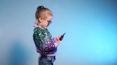 Pullu ceketiyle göz kamaştıran küçük bir kız, cep telefonuna sarılmış, ifadesi neşe dolu bir sürpriz. Genç, neşeli bir kız telefonda konuşur ve güler. Cep telefonu olan mutlu bir çocuk. Selfie