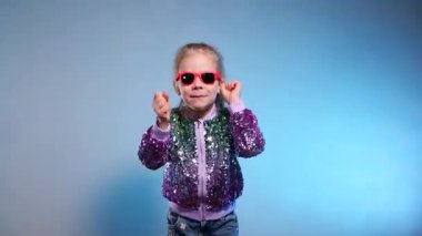 Stüdyoda renkli arka planda komik dans eden gülümseyen kız. Küçük hanım neşeyle gülüyor ve zevkle zıplıyor. Duygusal çocuk kameraya gülüyor. Disko partisi