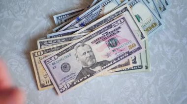 Bir yığın gevrek, dolar banknotları, becerikli ellerde tutuluyor. Adam kağıt para sayıyor. Bir Amerikan para akışı. Bir sürü Amerikan doları. ABD banknotlarının yakın plan görüntüsü. İşadamı elindeki banknotları sayar. Elinde parası olan adam..