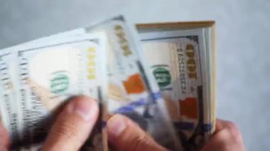 Bir yığın gevrek, dolar banknotları, becerikli ellerde tutuluyor. Adam kağıt para sayıyor. Bir Amerikan para akışı. Bir sürü Amerikan doları. ABD banknotlarının yakın plan görüntüsü. İşadamı elindeki banknotları sayar. Elinde parası olan adam..